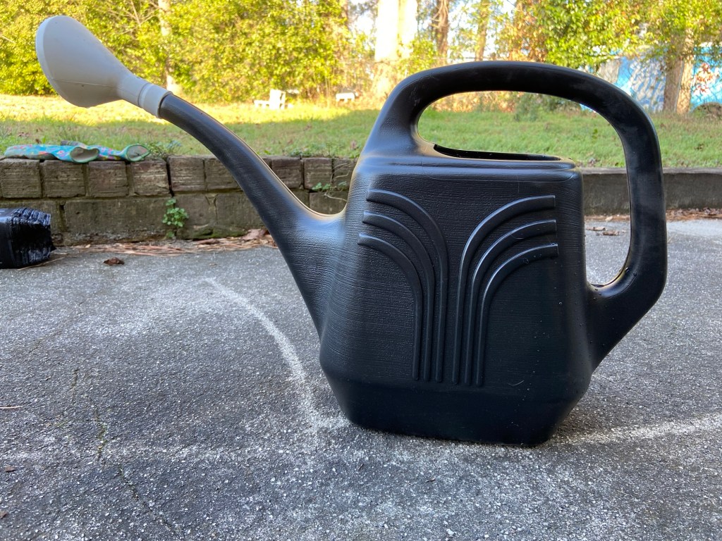 A photo of a black watering can with large sprinkler sprout